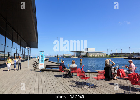 Menschen in Waterfront Café außerhalb der königlichen dänischen Spielhaus mit der Oper über das Wasser. Kopenhagen, Seeland, Dänemark Stockfoto