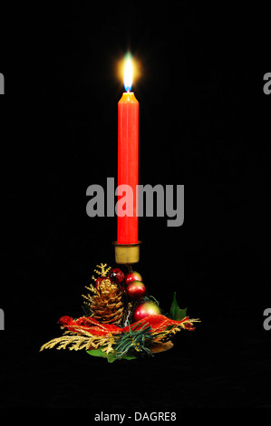 Rote Kerze in einem Weihnachts-Halter vor einem schwarzen Hintergrund. Stockfoto