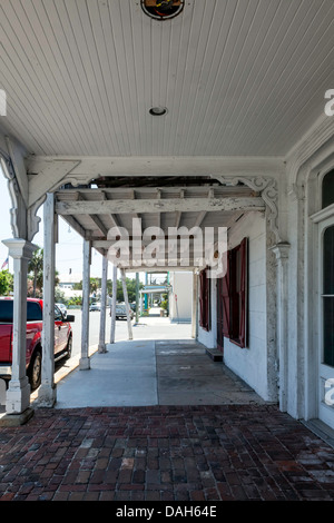 Blick auf die 2nd Street von überdachten Gehweg in historischen Geschäft Bezirk von Cedar Key, Florida. Roten Pick-up LKW Fahrzeuge geparkt. Stockfoto