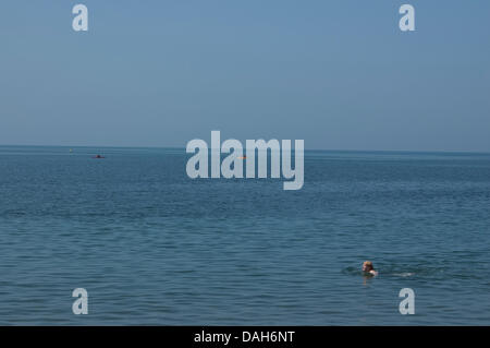 Aberystwyth, Wales, UK. 13. Juli 2013. Ein einsamer Schwimmer und drei Kajakfahrer nutzen das heiße Wetter und flache Meer in Aberystwyth, an einem Tag bei Temperaturen um 30 Grad Celsius in ganz Großbritannien zu erreichen festgelegt sind. Bildnachweis: Barry Watkins/Alamy Live-Nachrichten Stockfoto