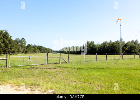 Eingezäunten Eingangstor schützt Rasen Landebahn hinaus in Cedar Key, Florida Bereich.  Windsack ist auf einen Metallmast montiert. Stockfoto