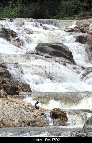 Touristen sitzen auf den Felsen am Ba Ho Wasserfall, Nha Trang, Vietnam Stockfoto