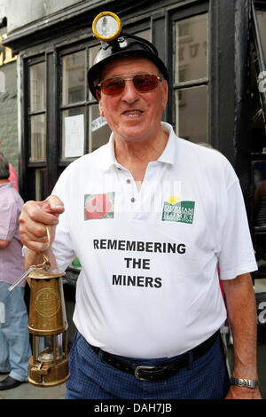 Ein Ex-Bergmann in der 129. Durham Miner Gala in Durham, England. Der Mann trägt einen Helm, trägt eine Davey Lampe und hat einen Slogan auf seinem T-shirt. Stockfoto