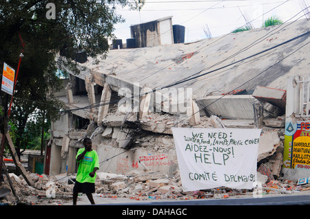 Ein haitianischer Mann geht vorbei an einem Schild fordert Hilfe und Versorgung im Anschluss an ein Erdbeben der Stärke 7,0, die 220.000 18. Januar 2010 in Port-au-Prince, Haiti Tote. Stockfoto