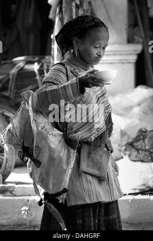 Schwarz / weiß Bild der Flower Hmong Frau trinkt Suppe am Coc Ly Markt, Provinz Lao Cai, Vietnam Stockfoto