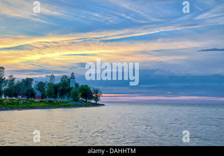 Leuchtturm am Horizont mit Sonnenuntergang Himmel im Hintergrund. Stockfoto