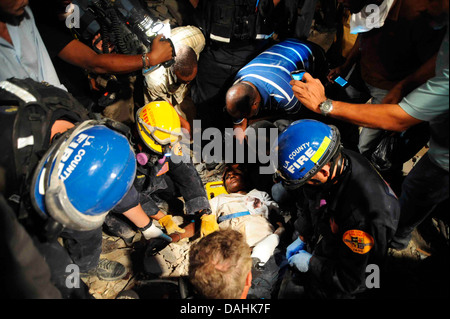 Mitglieder des Los Angeles County Fire Department Search and Rescue Team retten eine haitianische Frau aus einem eingestürzten Gebäude im Anschluss an ein Erdbeben der Stärke 7,0, die 220.000 Menschen 17. Januar 2010 in Port-au-Prince, Haiti getötet. Die Frau überlebt 5 Tage ohne Nahrung oder Wasser in den Trümmern. Stockfoto