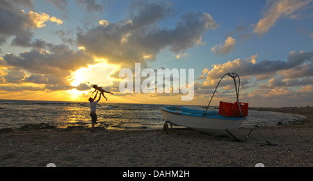 Gestrandeter Fishingboat bei Sonnenuntergang am Strand in der Nähe von Akko, Israel Stockfoto