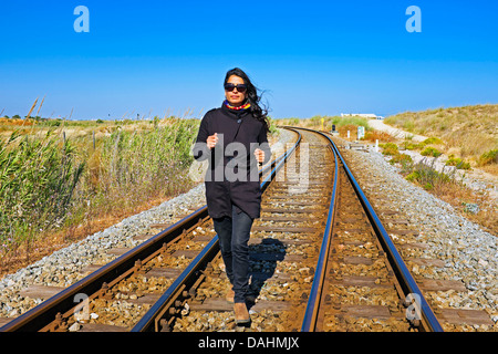 Junge schöne Frau, die auf einem Bahngleis Stockfoto