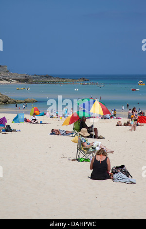 Menschen, die am Strand in St. Ives Cornwall Porthminster Strand Menschen Zuflucht vor der Sonne unter den Sonnenschirmen entspannen Stockfoto