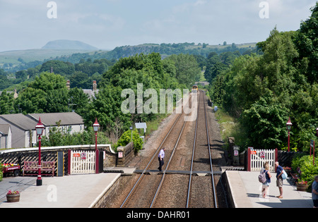 Ein Sprinter Personenzug fährt Station niederlassen, North Yorkshire, für Carlisle, Großbritannien gebunden. Ingleborough Hügel sichtbar am Horizont. Stockfoto