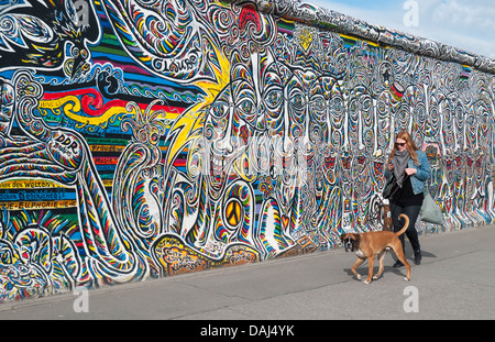 Frau geht Hund von Wir Sind Ein Volk Gemälde von Schamil Gimajev, East Side Gallery, Berliner Mauer (Berliner Mauer), Deutschland Stockfoto