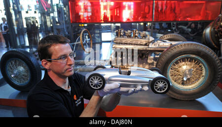 Ein Restaurator Tim Luecke präsentiert ein Modell der Awtowelo 650 vor das Gehäuse von der original-Auto im Industriemuseum in Chemnitz, Deutschland, 24. März 2011. Der Rennwagen wurde von der sowjetischen Autofirma Awtowelo ca. 1950/52 erbaut. Heute gibt es nur drei von diesen Autos. Foto: Hendrik Schmidt Stockfoto