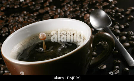 (Dpa Datei) - eine Archiv Bild, datiert 20. Februar 2007, zeigt einen Tropfen Kaffee Spritzwasser in eine Kaffeetasse, umgeben von Kaffeebohnen in Frankfurt am Main, Deutschland. US-Wissenschaftler haben zwei Kaffee-Gene gefunden, in der menschlichen DNA, die das Verlangen nach Kofein beeinflussen. Foto: Tobias Felber Stockfoto