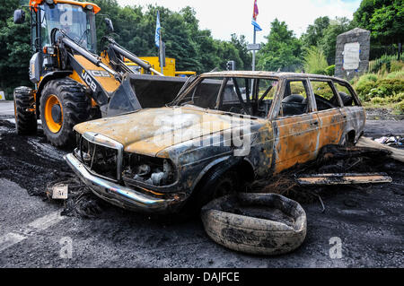 Belfast, Nordirland. 15. Juli 2013 - Umweltministerium verwenden einen JCB Bagger um Schmutz von der Straße nach einer Nacht der Ausschreitungen zu löschen. Stockfoto