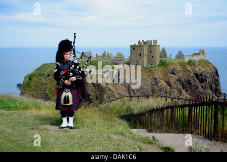 Horizontale Bild einer Piper spielt Dudelsack vor Dunnottar Castle, Schottland, UK, 8. Weltwunder nominiert Stockfoto