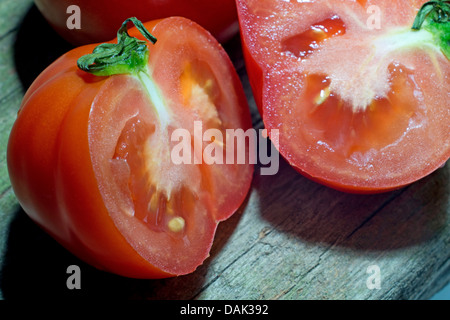 Garten-Tomaten (Solanum Lycopersicum, Lycopersicon Esculentum), liegend auf einem Holzbrett in Scheiben geschnitten Stockfoto