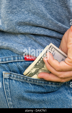 Mans Hand setzen Dollarnoten in seiner Jean-Tasche Stockfoto