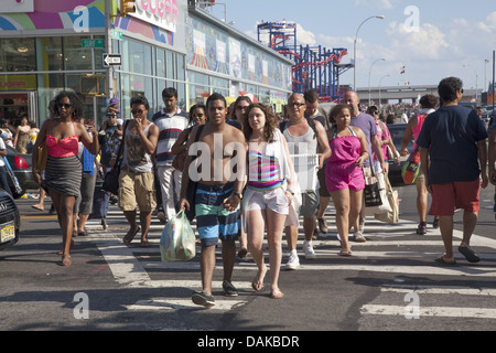 Menschen überqueren Surf Avenue auf dem Heimweg nach einem Tag am Strand von Coney Island, Brooklyn, NY. Stockfoto