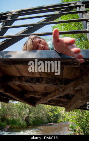 Frau, die Hand auszustrecken, von der Brücke. Stockfoto