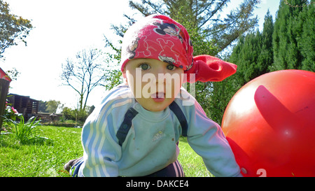 Kleinkind krabbeln auf einer Wiese neben einem Hop Ball, Deutschland Stockfoto