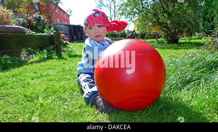 Kleinkind im Garten auf der Wiese sitzen und spielen mit einem Hop Ball, Deutschland Stockfoto