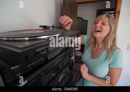 Frau eine Schallplatte auf einem Plattenspieler Nadel aufsetzen. Stockfoto