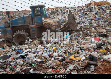 Müll türmt sich in Deponie jeden Tag während LKW mit Sand für sanitäre Zwecke abdeckt. Stockfoto