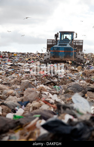 Müll türmt sich in Deponie jeden Tag während LKW mit Sand für sanitäre Zwecke abdeckt. Stockfoto