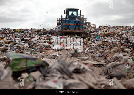 Müll türmt sich in Deponie jeden Tag während LKW mit Sand für sanitäre Zwecke abdeckt. Stockfoto