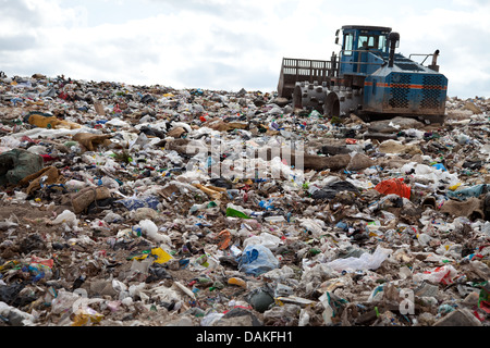 Müll türmt sich in Deponie jeden Tag während LKW mit Sand für sanitäre Zwecke abdeckt. Stockfoto