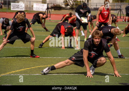 Multi-ethnischen Highschool-Athleten Protze mit Flexibilitätsübungen wie sie Frühjahr Fußballtraining in Kalifornien beginnen. Stockfoto