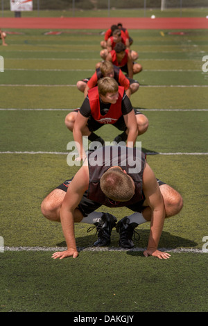 Multi-ethnischen Highschool-Athleten Protze mit Flexibilitätsübungen wie sie Frühjahr Fußballtraining in Kalifornien beginnen. Stockfoto