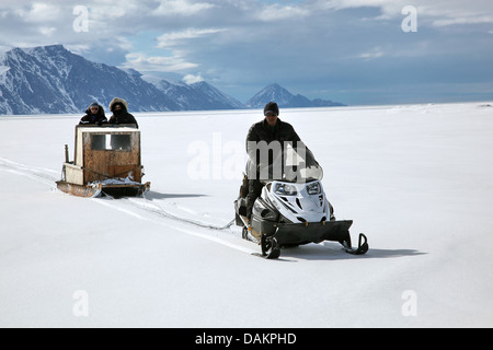 drei Personen mit Schlitten in der arktischen Landschaft, Kanada, Nunavut Stockfoto