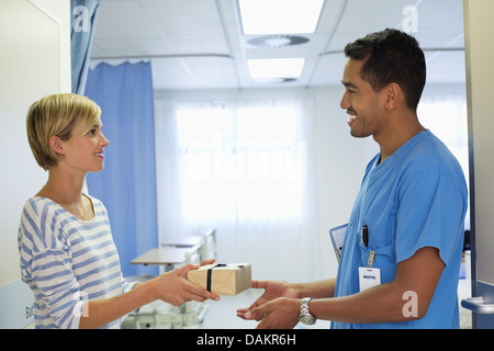 Patienten geben Krankenschwester Geschenk im Krankenhaus Stockfoto