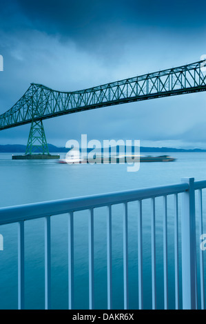 Coole Stimmung Bild, vertikale Format barge Schifffahrt auf dem Columbia River im Winter, Astoria-Megler Bridge mit Vordergrund Handlauf. Kopieren Sie Platz. Oregon Stockfoto