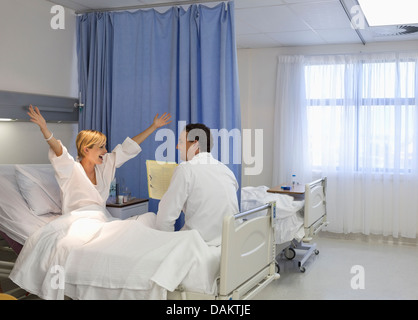 Arzt im Gespräch mit jubelnden Patienten im Krankenzimmer Stockfoto