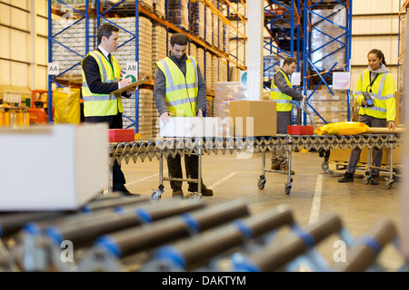 Arbeitnehmer, die Pakete auf Förderband im Lager überprüfen Stockfoto