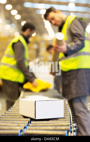 Arbeitnehmer, die Pakete auf Förderband im Lager überprüfen Stockfoto