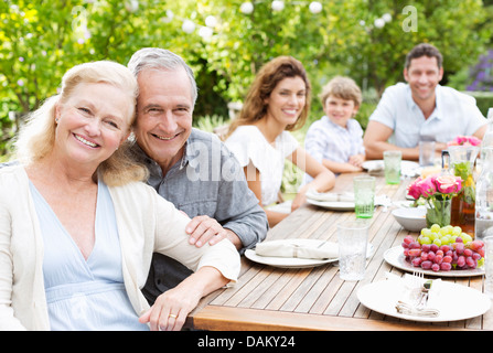 Familie lächelnd am Tisch im freien Stockfoto