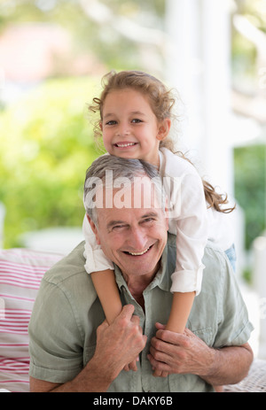 Älterer Mann mit Enkelin Huckepack Stockfoto
