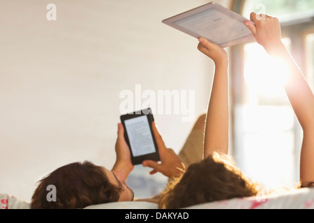 Paar mit Tablet-PCs im Bett Stockfoto