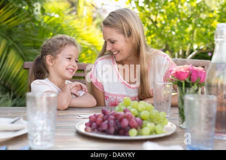 Mutter und Tochter lächelnd am Tisch im freien Stockfoto