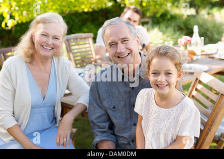 Älteres Paar und Enkelin lächelnd im freien Stockfoto