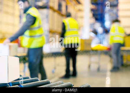 Arbeitnehmer, die Boxen auf Förderband im Lager prüfen Stockfoto