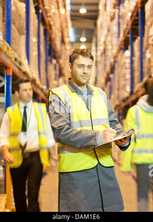 Arbeiter in Zwischenablage im Warehouse schreiben Stockfoto