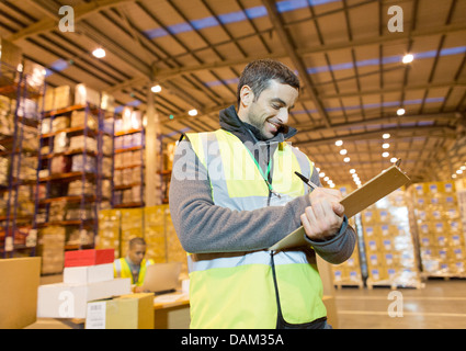 Arbeiter in Zwischenablage im Warehouse schreiben Stockfoto