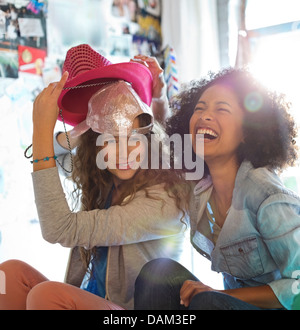 Frauen spielen mit Hüten im Schlafzimmer Stockfoto