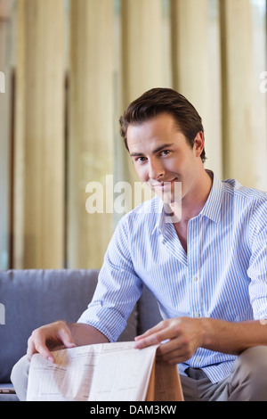 Mann-Betrieb-Zeitung auf sofa Stockfoto