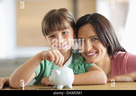Mutter und Tochter Füllung Sparschwein Stockfoto